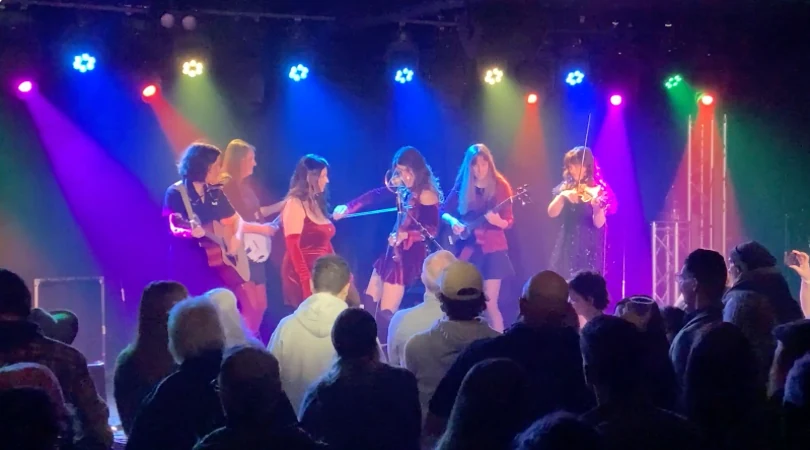 Jenny & The StreetWalkers performing under colorful stage lights for a live audience